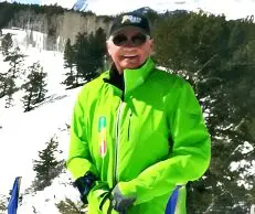Person wearing a bright green jacket and sunglasses in a snowy outdoor setting.