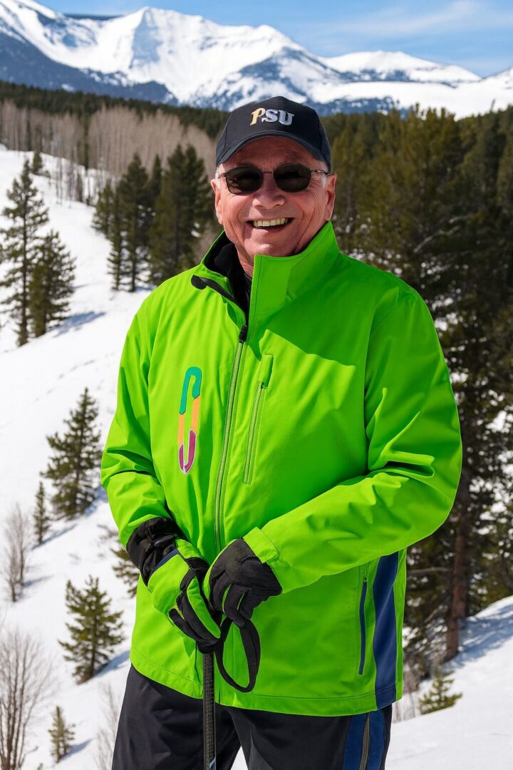 Man in bright green jacket smiling in snowy mountain setting.